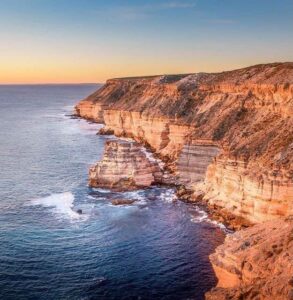 Sunset lighting up the dramatic limestone cliffs of Kalbarri’s coastline, with the Indian Ocean waves crashing below.